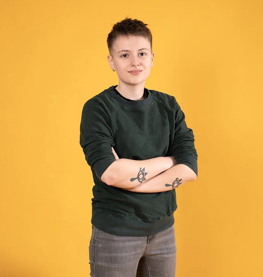 Samira Hobi vor gelbem Hintergrund, mit verschränkten Armen